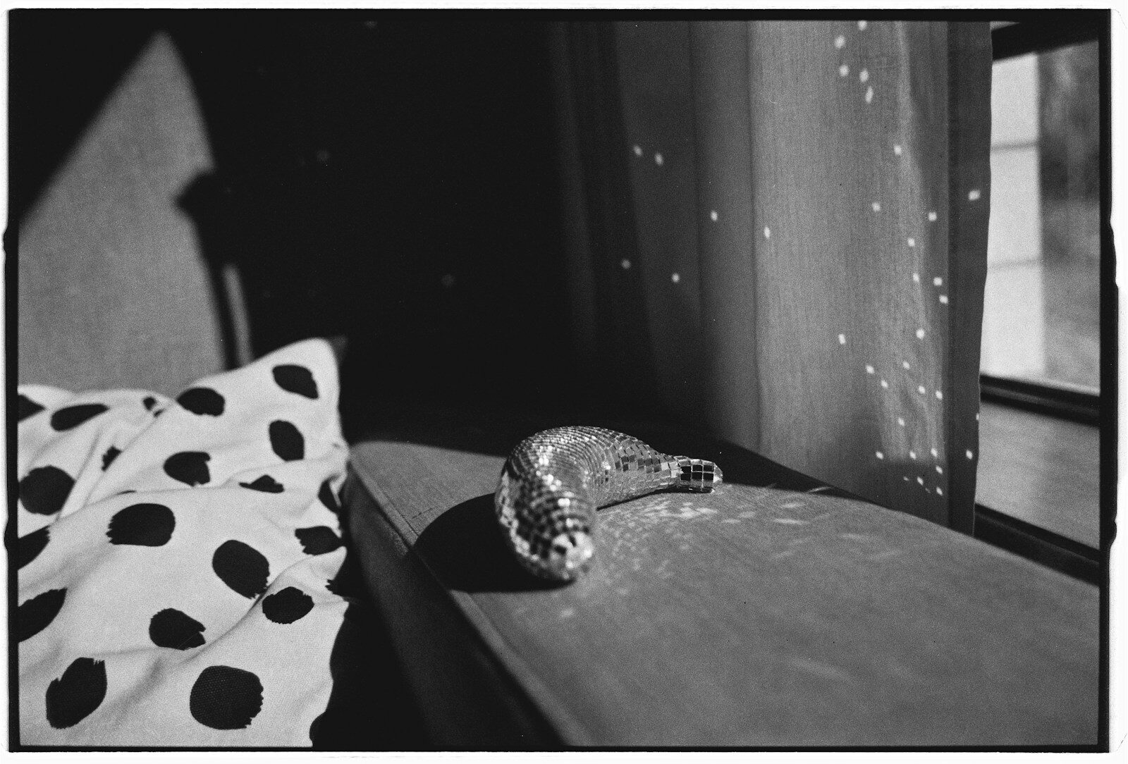 A sparkly ornament rests on a windowsill.