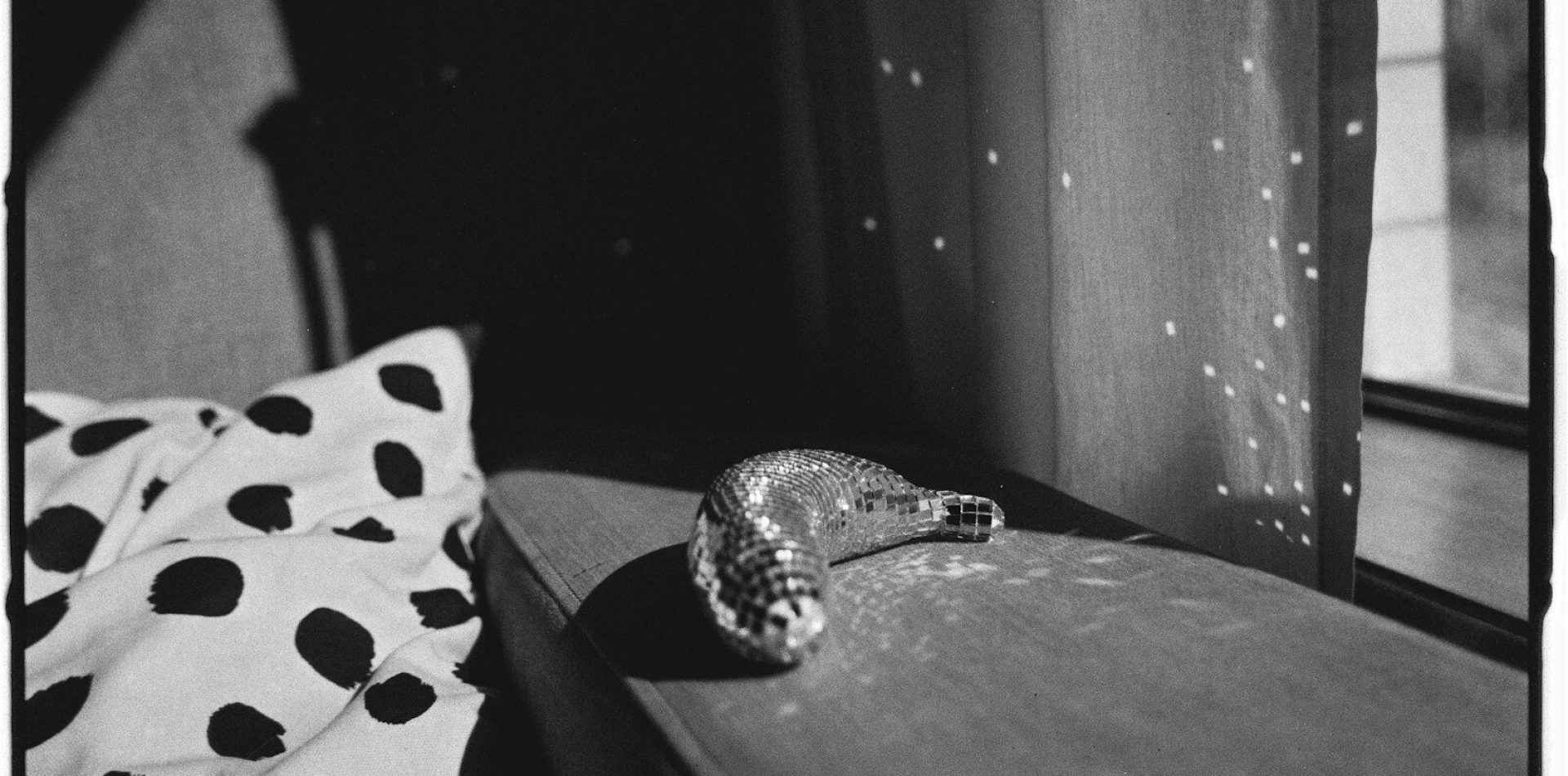 A sparkly ornament rests on a windowsill.