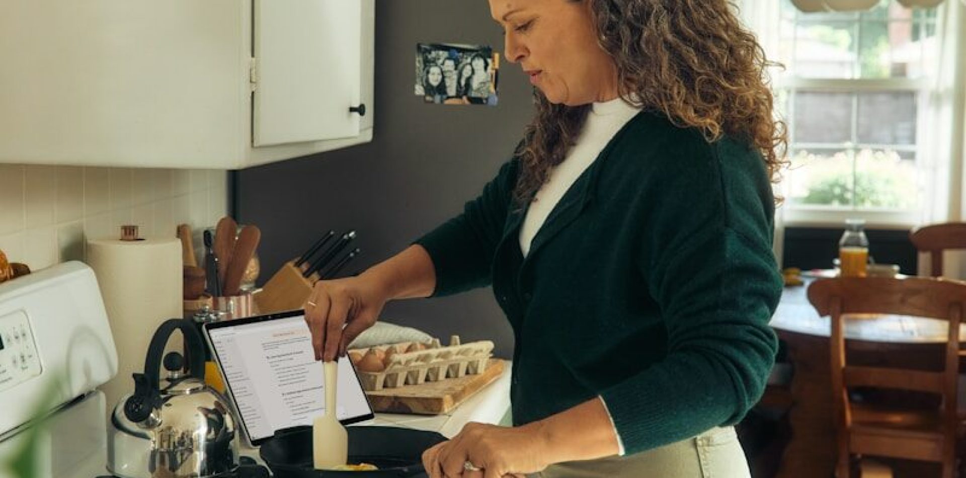 Woman following recipe on tablet in kitchen.
